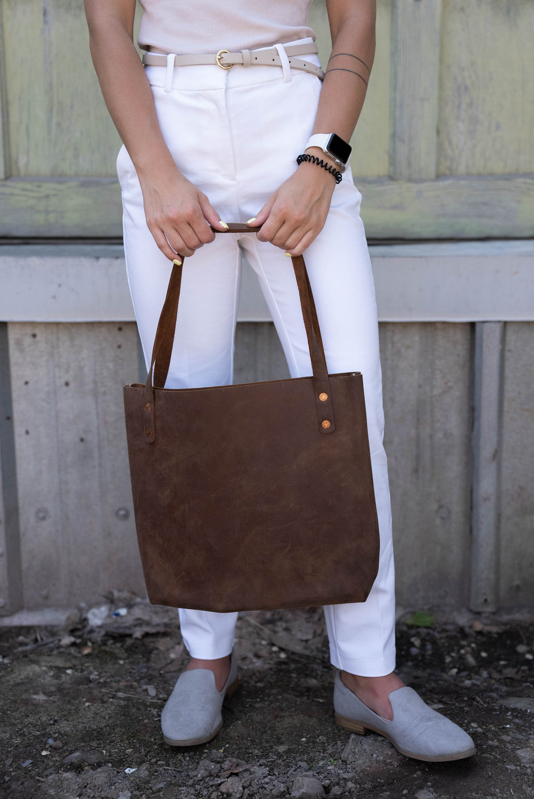 Missoula, Montana Chrome Tote bag for sale. Made with local leather and handmade by Snowday leather. The leather purse is fashioned by premium white pants, white smart watch and elegant off white skinny belt by a Missoula local woman.